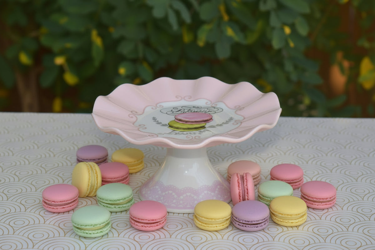 Decorative pink and white ceramic cake stand with a scalloped edge on a patterned surface.
