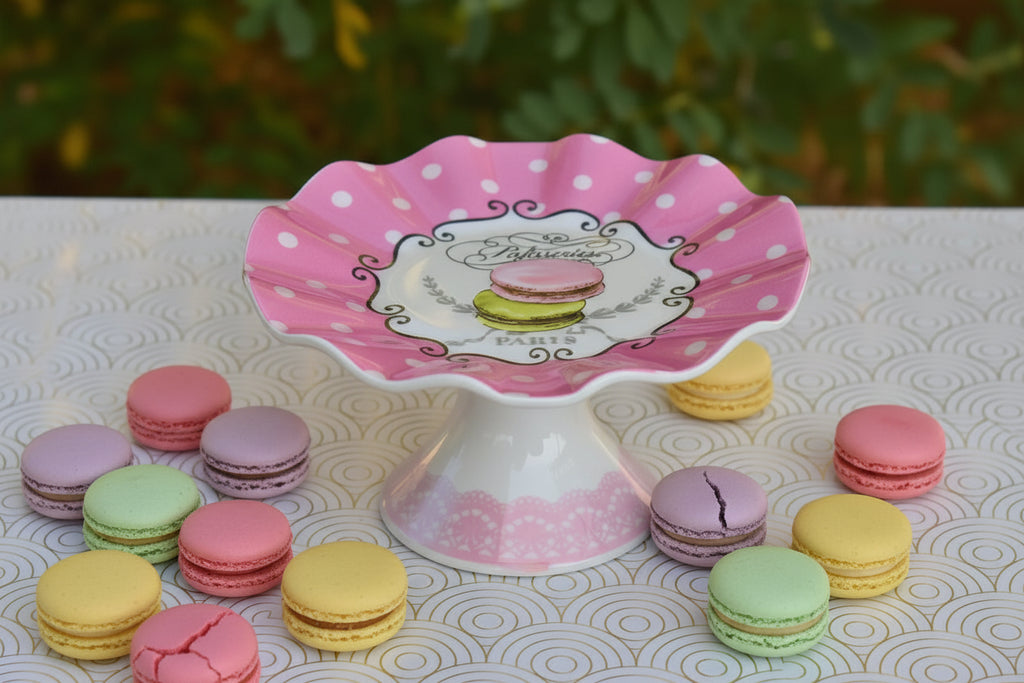 Pink polka dot cake stand with a decorative emblem on a patterned surface.