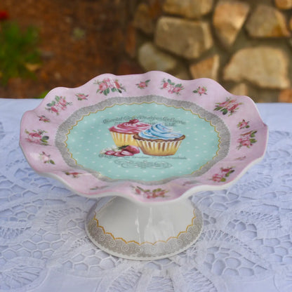 Decorative cake stand with floral design and cupcake illustration on a lace tablecloth.