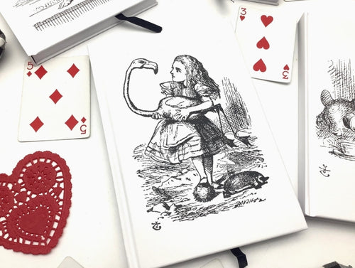 Playing cards with illustrations of Alice in Wonderland on a white surface.