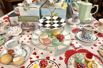 Decorative table setting with a clock-shaped stand, teacups, and other tableware.