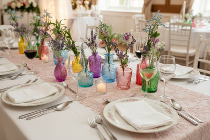 Assorted colorful glass vases with floral arrangements on a white background